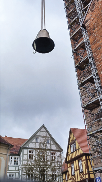 Eine Glocke schwebt am Kran zum Turm der Perleberger Kirche